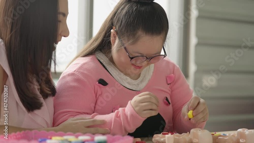 young girl with autism is practicing fun playing with toys at home with his mother. Autistic young students are learning with teachers happily. Training for intelligence restoration for autism.