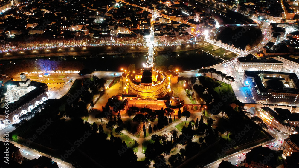 Aerial drone night view of illuminated Castel Sant'Angelo and iconic Saint Peter Basilica in city of Vatican at the background, Rome historic centre, Italy