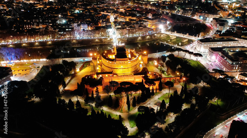 Aerial drone night view of illuminated Castel Sant'Angelo and iconic Saint Peter Basilica in city of Vatican at the background, Rome historic centre, Italy