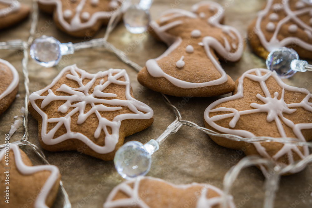 Handmade gingerbread cookies with icing, selective focus, decorated with Christmas lights, close-up. 