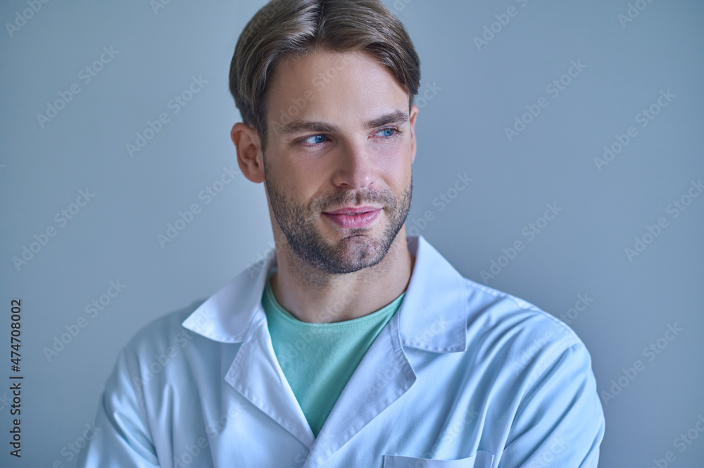 Man in white coat looking to side indoors