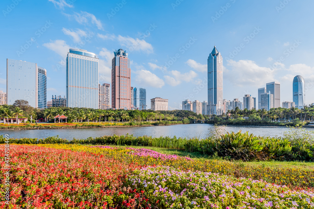 Obraz premium Sunny scenery of the flower bushes and the International Trade CBD complex in Haikou Wanlv Park, Hainan, China