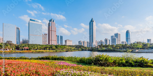 Sunny scenery of the flower bushes and the International Trade CBD complex in Haikou Wanlv Park, Hainan, China photo