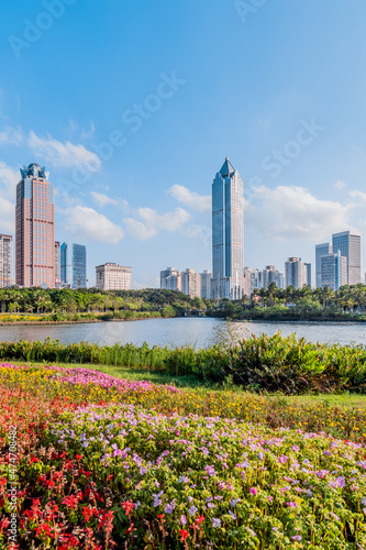 Sunny scenery of the flower bushes and the International Trade CBD complex in Haikou Wanlv Park, Hainan, China © Govan