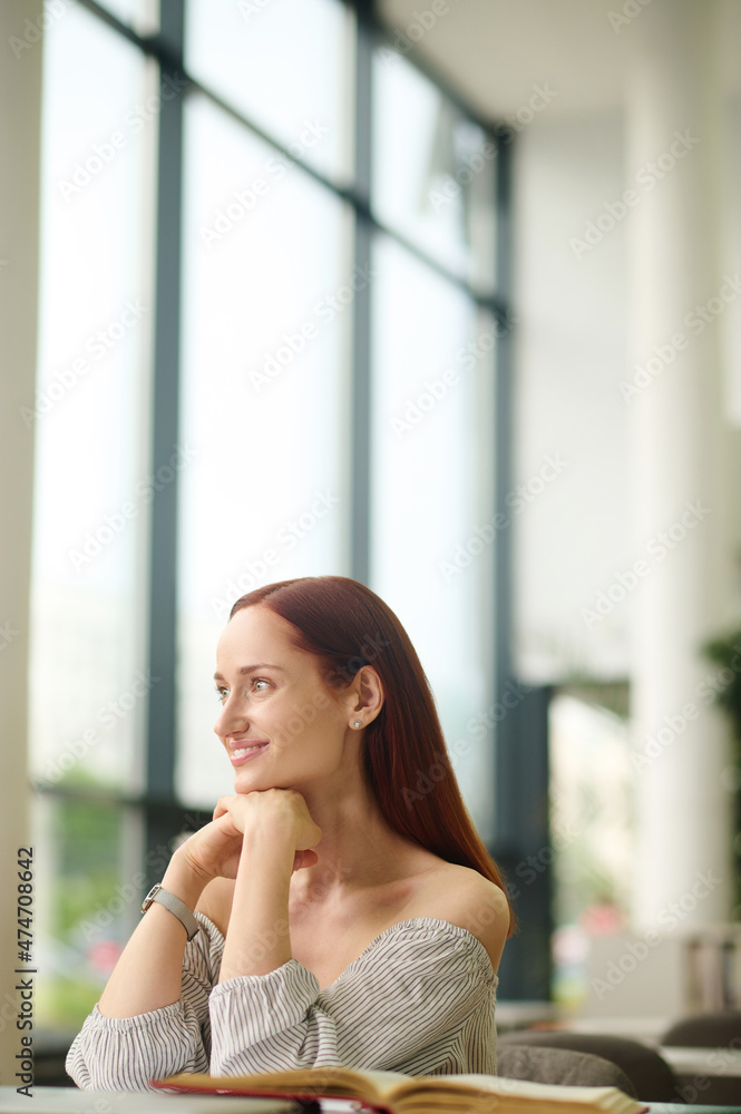 Fototapeta premium Woman sitting at table looking aside