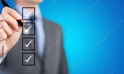 Young man checking boxes with list of options on the background