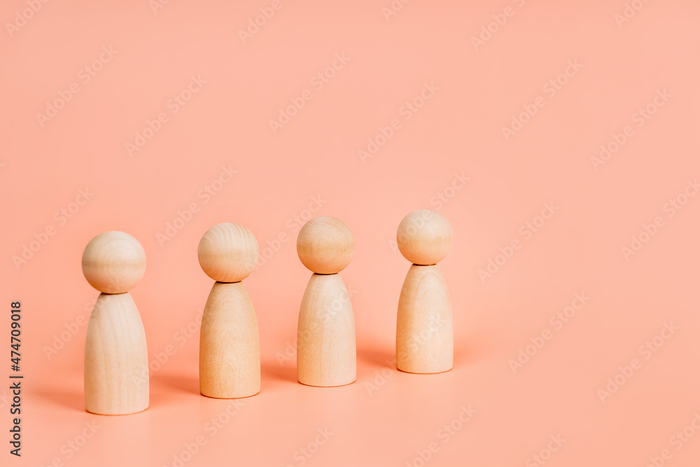 Abstract wooden toy figures stand in a row on a pink background. Concept of employees in a team, banner format Abstract wooden toy figures stand in a row on a pink background. Concept of employees in a team, banner format