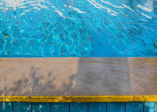 de focused frame on side of swimming pool and water blue surface of the water. Clean water runs down the edges of pool