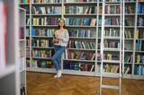 Woman holding books looking to side in library