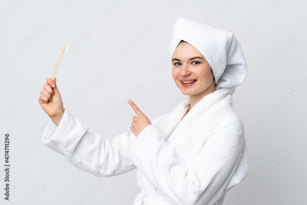 Young woman in a bathrobe holding toothbrush and pointing it Young woman in a bathrobe holding toothbrush and pointing it