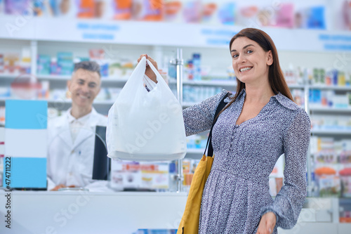 Long-haired woman looking contented after buying goods in a drugstore photo