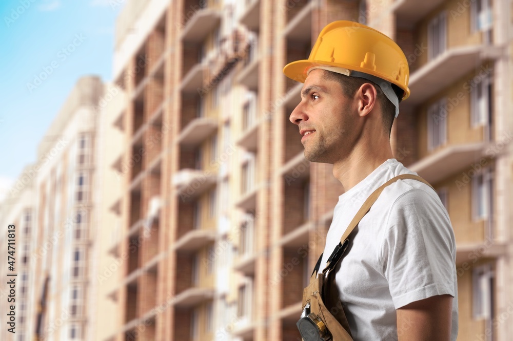 Male engineer handsome or architect with safety helmet in construction site. Standing at modern building construction.