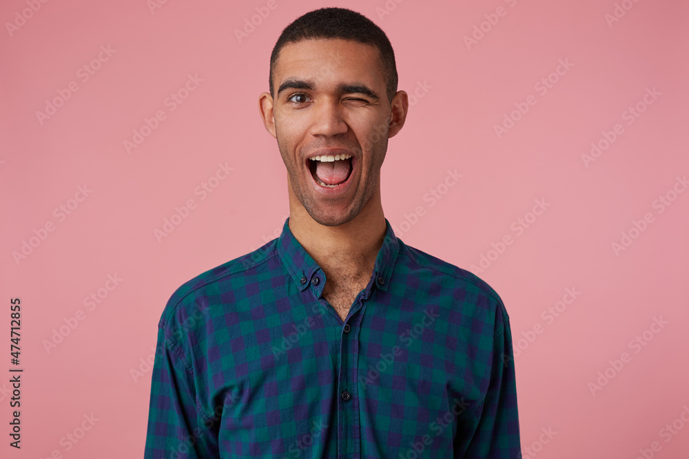 studio portrait of middle age middle eastern man wears blue checkered shirt smiles broadly, feels excited and wink. isolated over pink background studio portrait of middle age middle eastern man wears blue checkered shirt smiles broadly, feels excited and wink. isolated over pink background