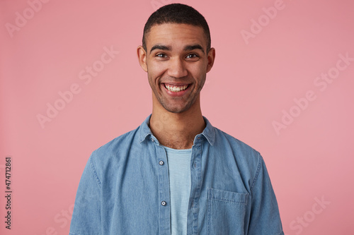 studio portrait of middle age middle eastern man wears blue shirt smiles broadly and feels happy. isolated over pink background © timtimphoto