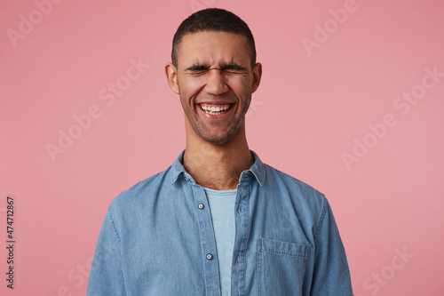 studio portrait of middle age middle eastern man wears blue shirt smiles and laughs, feels happy, isolated over pink background