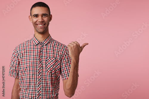 studio portrait of middle age middle eastern man wears blue shirt points aside with positive, happy facial expression isolated over pink background photo