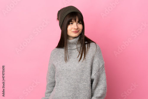 Teenager Ukrainian girl with winter hat isolated on white background standing and looking to the side