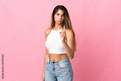 Young caucasian woman isolated on pink background frustrated and pointing to the front © luismolinero