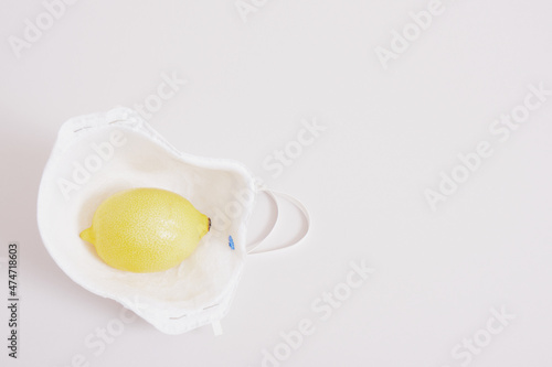 a creative concept, medical mask and lemon on a gray background. health care.