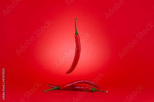 Three of Chili peppers isolated on red background. photo