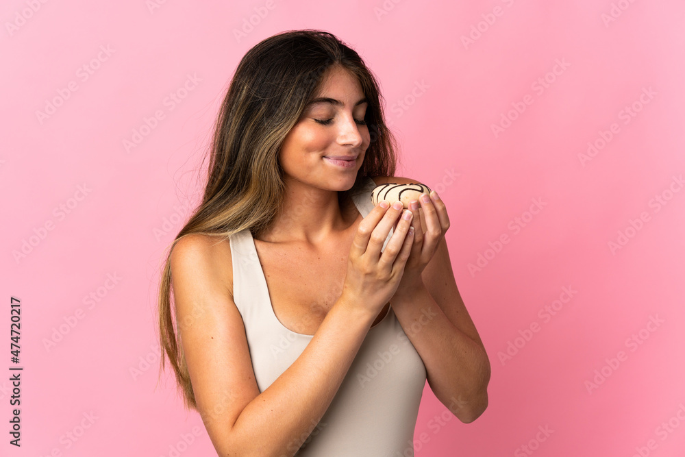 Young caucasian woman isolated on pink background holding a donut Young caucasian woman isolated on pink background holding a donut