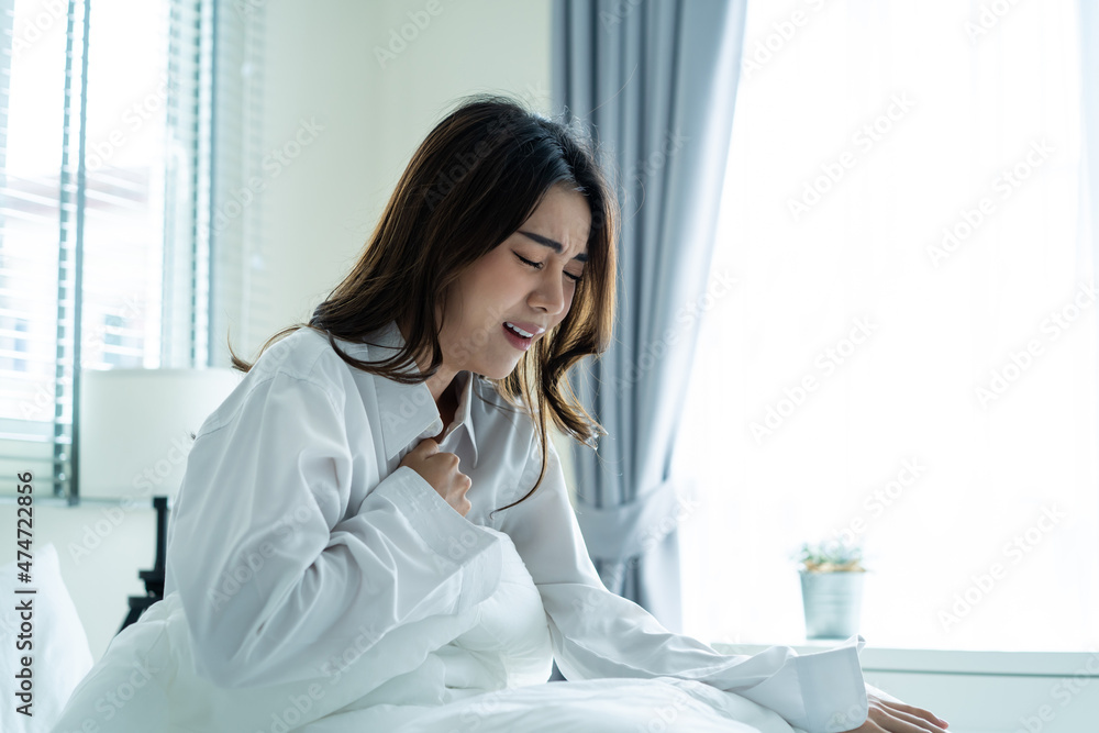 Asian beautiful sick girl in pajamas getting up from sleep in bedroom. Asian beautiful sick girl in pajamas getting up from sleep in bedroom.