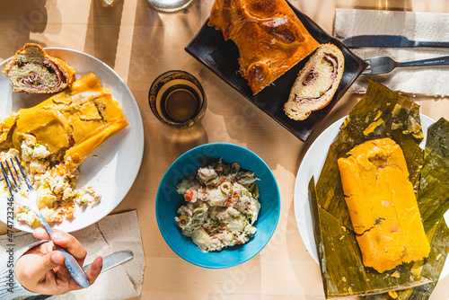 venezuelan christmas food display on table with traditional hallacas, pan de jamon or ham bread, and mixed salad, with cutlery and ready. traditional dishes of venezuelan cuisine