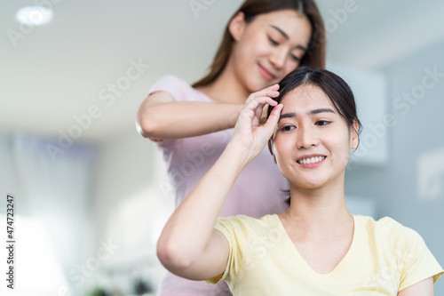 Asian beautiful lesbian women couple combing girlfriends hair in house