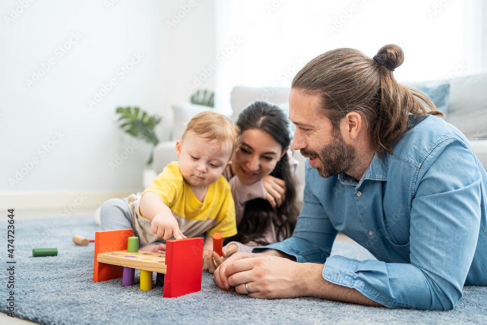 Caucasian happy loving parent play with baby toddler in living room. Caucasian happy loving parent play with baby toddler in living room.