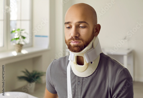 Canvas Print Unwell young Caucasian man with neck collar suffer from back fracture or trauma