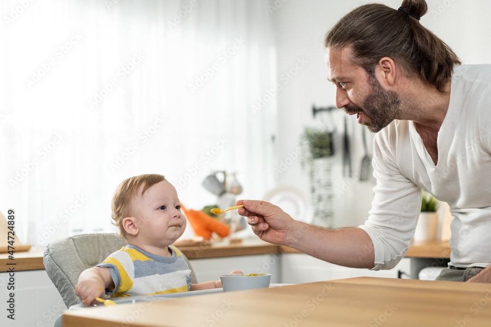 Caucasian beautiful father take care of baby boy toddler in kitchen.