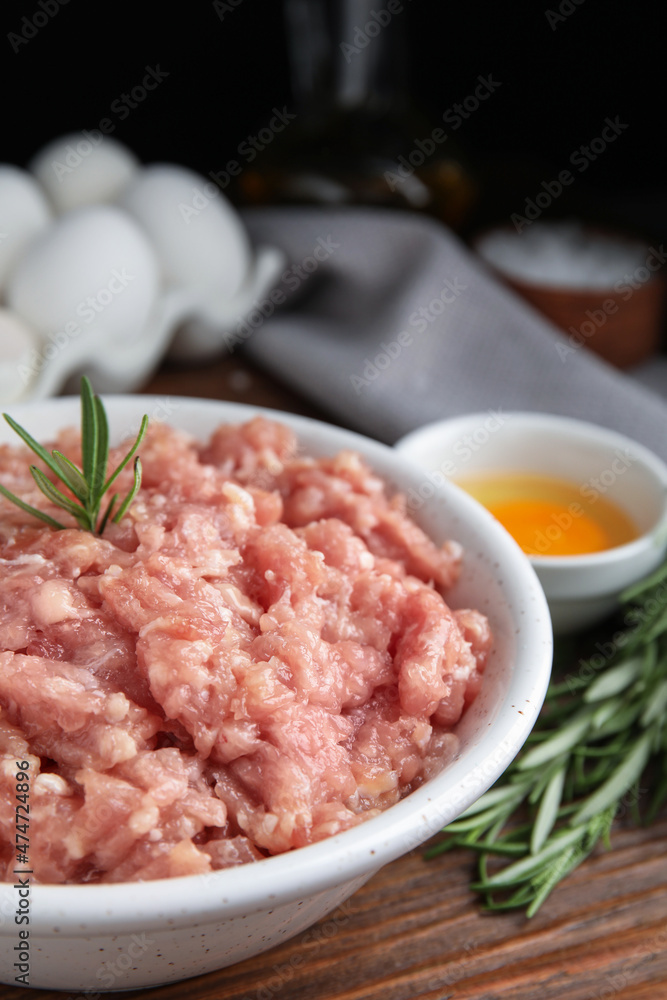 Raw chicken minced meat with rosemary on wooden table, closeup