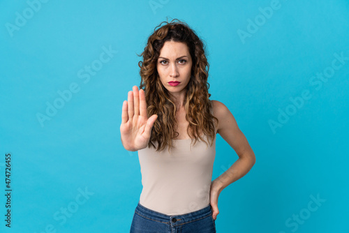 Young caucasian woman isolated on blue background making stop gesture © luismolinero