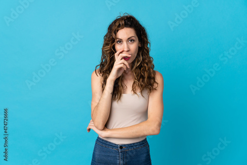 Young caucasian woman isolated on blue background surprised and shocked while looking right