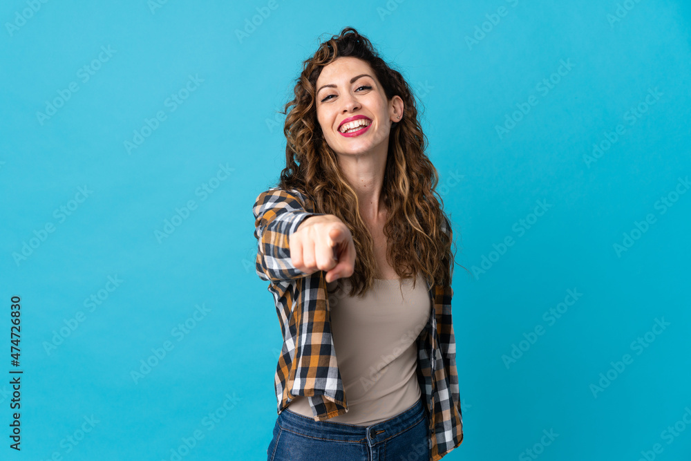 Young caucasian woman isolated on blue background pointing front with happy expression Young caucasian woman isolated on blue background pointing front with happy expression