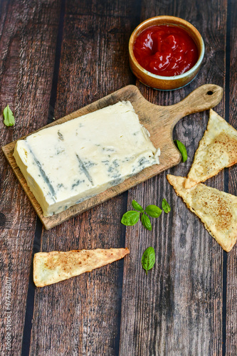 Gorgonzola cheese on cutting board with fresh  basil . Veined Italian  blue cheese.