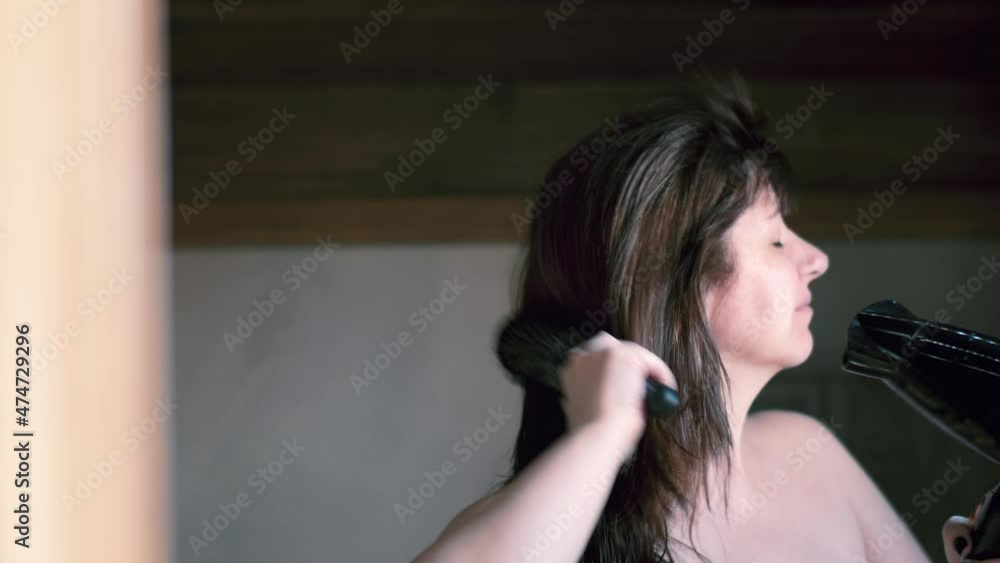 brunette woman in the bathroom near the mirror dries her hair with a hairdryer, moving camera, cinematic brunette woman in the bathroom near the mirror dries her hair with a hairdryer, moving camera, cinematic