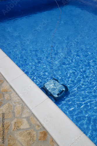 Cleaning the pool floor with an underwater vacuum cleaner, pool maintenance concept. © triocean