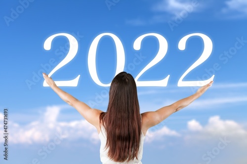 Young woman greets the 2022 against clouds