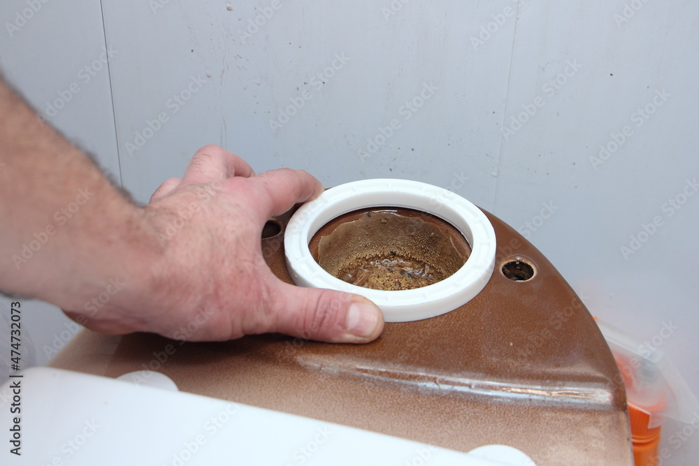 Plumber hand install new O-ring sealing on the old ceramic brown toilet seat drain fitting close up, DIY WC repair at home