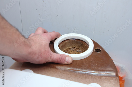Obraz na płótnie Plumber hand install new O-ring sealing on the old ceramic brown toilet seat drain fitting close up, DIY WC repair at home w salonie
