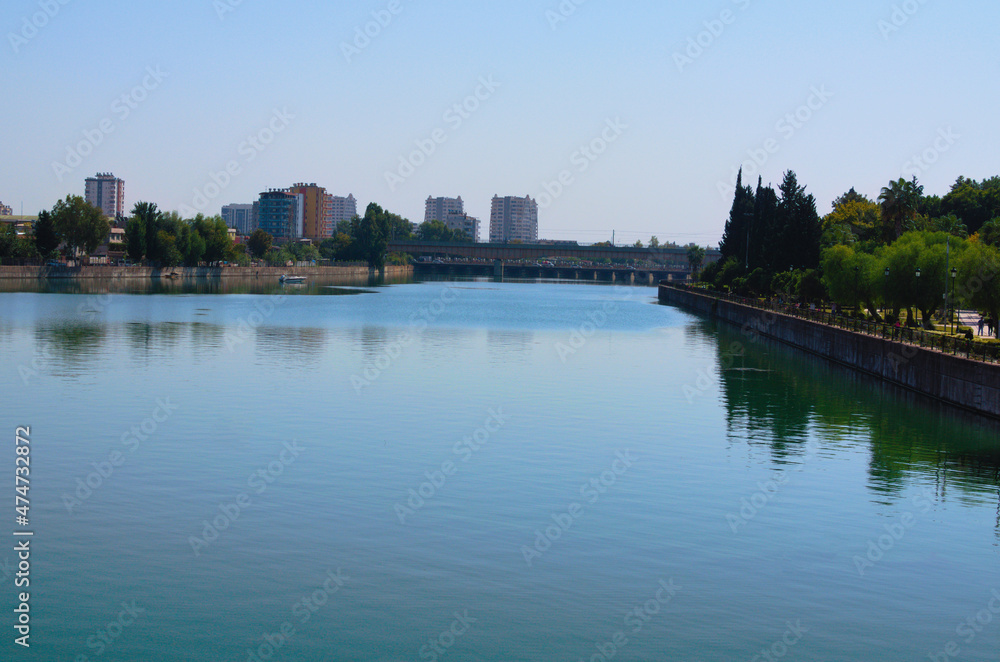 Scenic cityscape of Adana. High-rise buildings and bridge over Seyhan River. Blue sky background