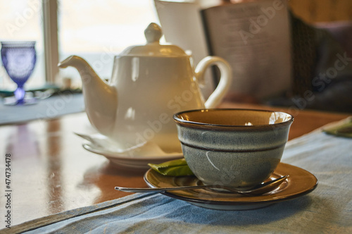 Tea pot with tea cup with spoon and sugar on the wooden brown table