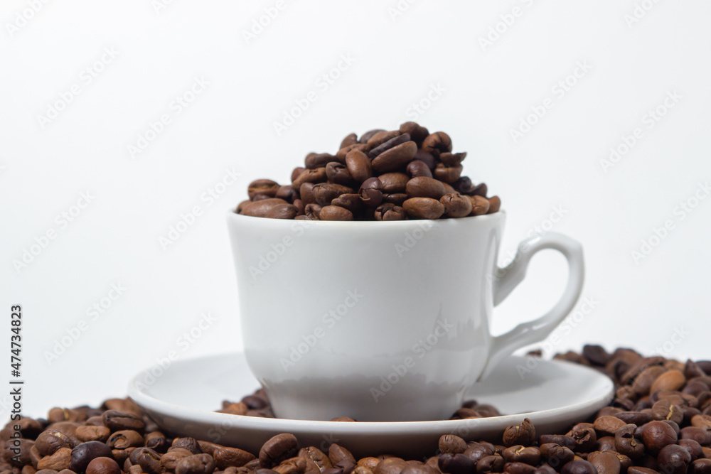 Coffee beans on a white background. A coffee cup full of coffee beans. Large serving of caffeine Coffee beans on a white background. A coffee cup full of coffee beans. Large serving of caffeine