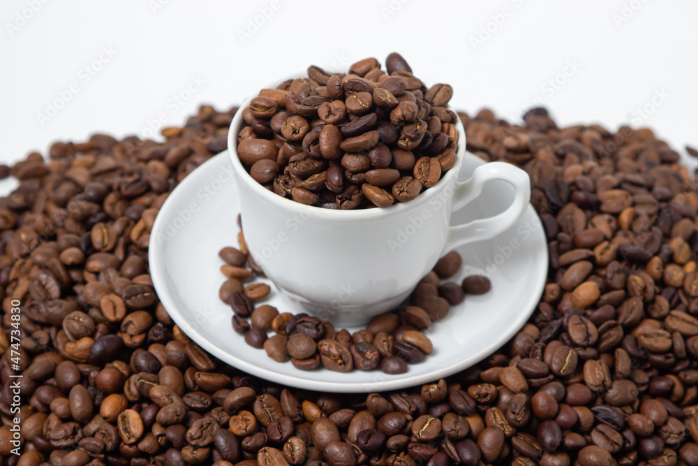 Fototapeta premium Coffee beans on a white background. A coffee cup full of coffee beans. Large serving of caffeine