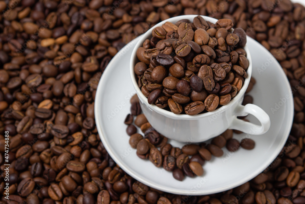 Coffee beans on a white background. A coffee cup full of coffee beans. Large serving of caffeine Coffee beans on a white background. A coffee cup full of coffee beans. Large serving of caffeine