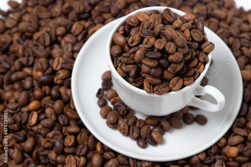 Coffee beans on a white background. A coffee cup full of coffee beans. Large serving of caffeine