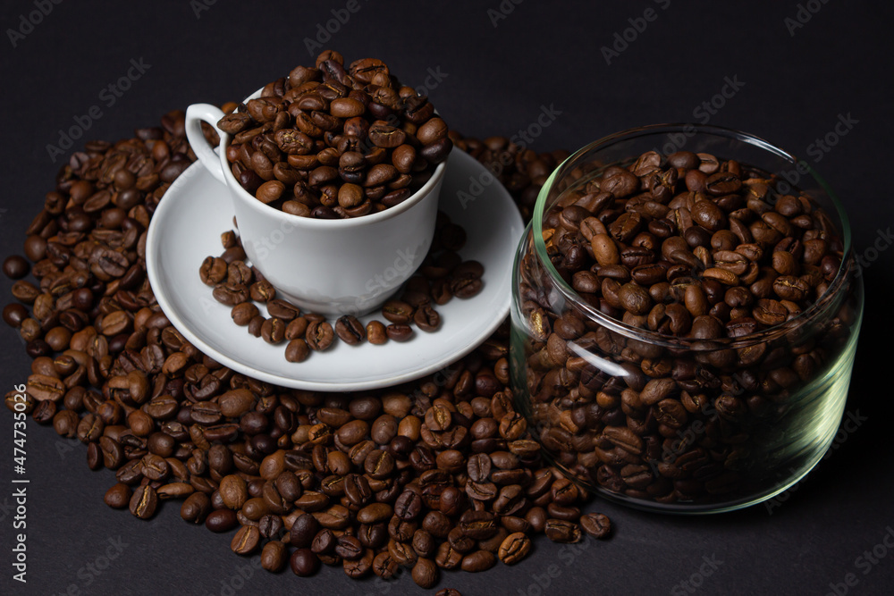 Coffee beans on a black background. A coffee cup full of coffee beans. Large serving of caffeine