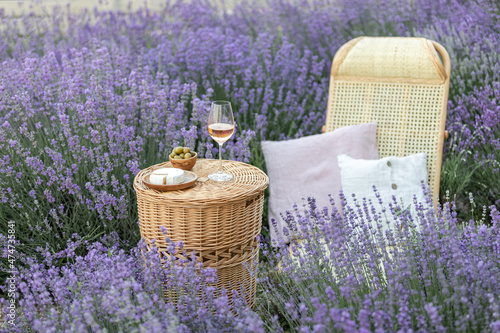 Glass of white wine in a lavender field. Violet flowers on the background.