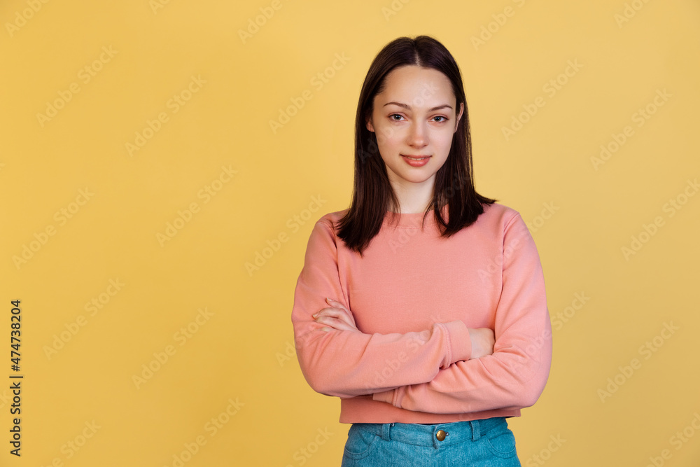 Portrait of young beautiful calm girl looking at camera isolated on yellow studio background. Concept of human emotions Portrait of young beautiful calm girl looking at camera isolated on yellow studio background. Concept of human emotions